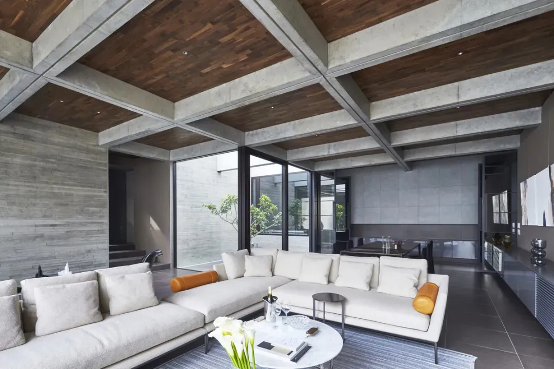 Modern industrial living room with concrete ceiling, white furniture, and open space.