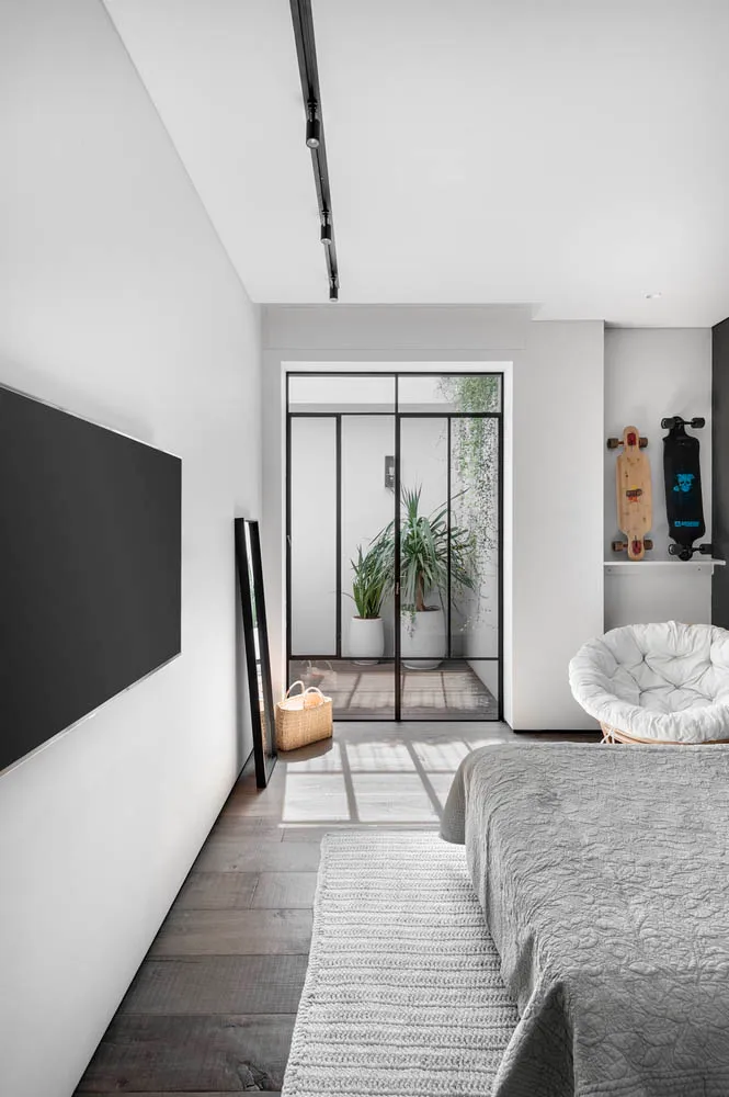 A contemporary bedroom with a white wall, wooden floor, and minimalist design.