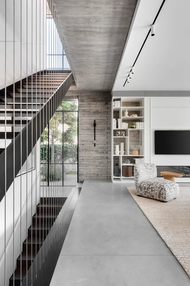 Modern minimalist living room with concrete flooring, glass walls, and metal accents.