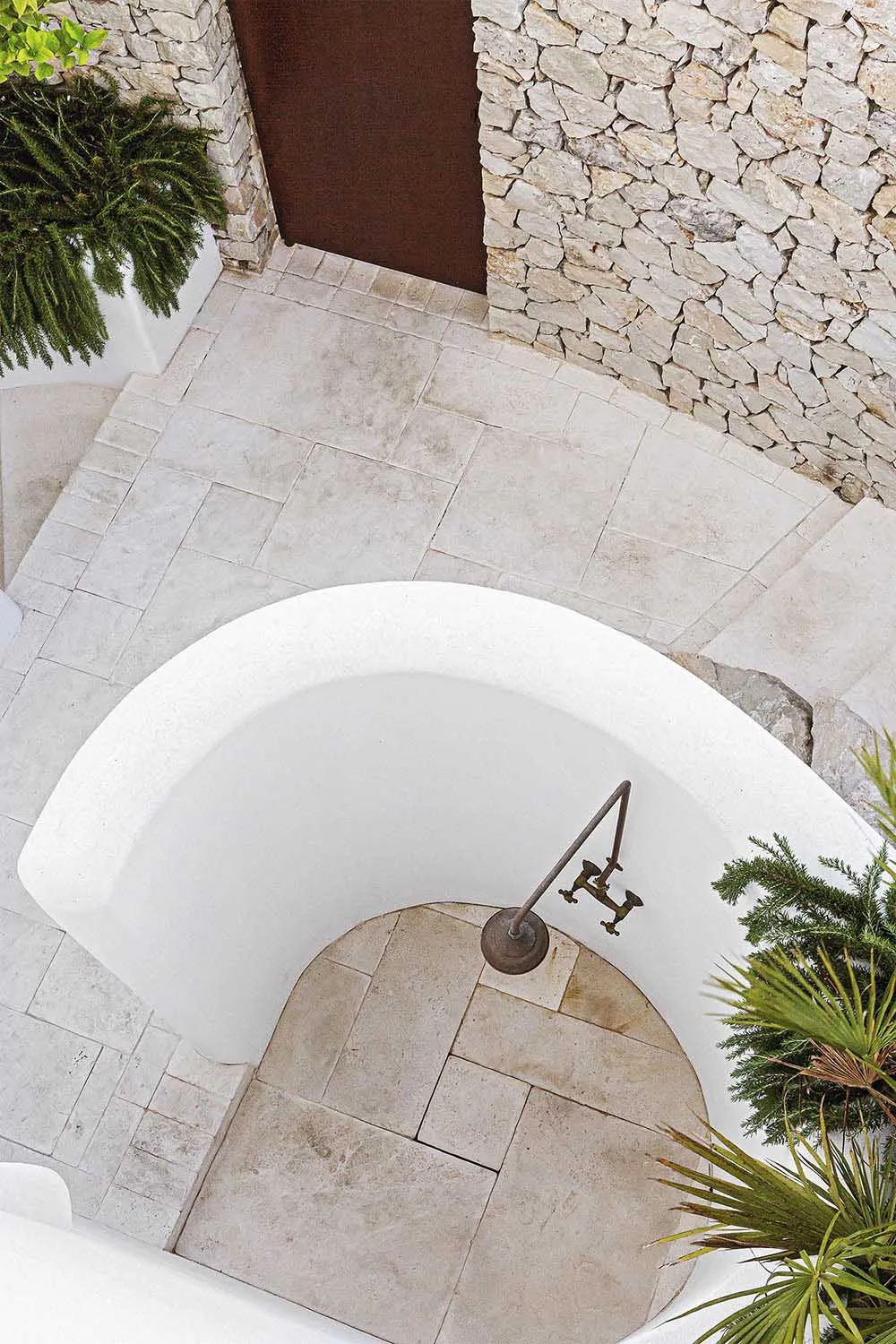 Traditional stone and marble bathroom design with rustic details and a vintage bathtub faucet.