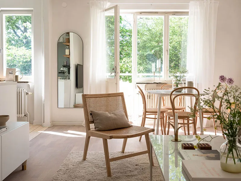 A minimalist living room with wood furniture, glass accents, and sheer fabric curtains.
