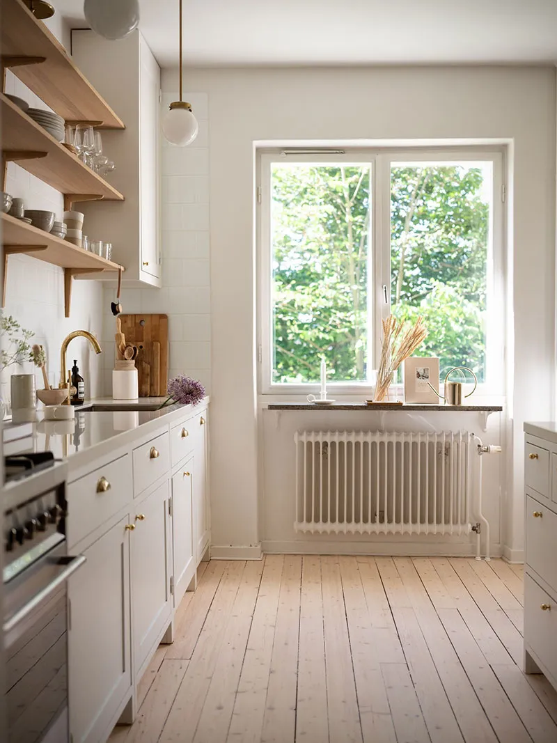 Modern, minimalist residential kitchen with white oak flooring, marble countertops, and open-plan design.
