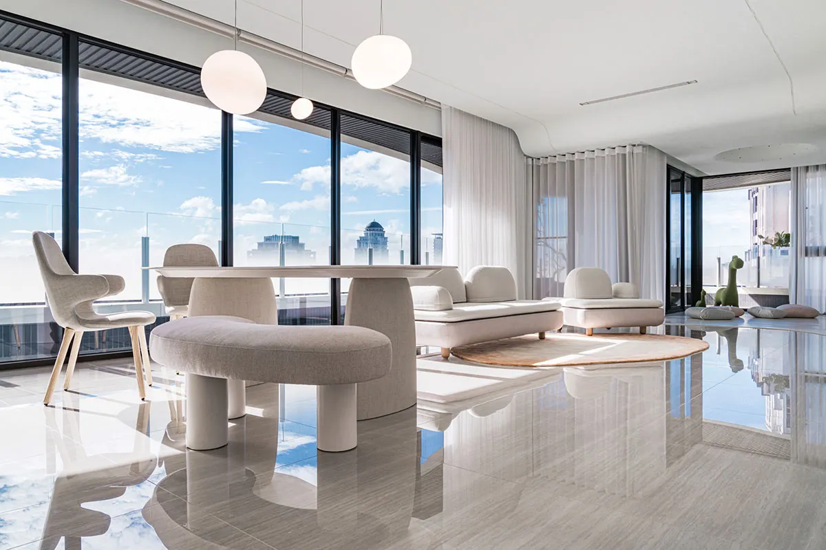 Modern living room featuring a light gray marble floor, minimalist furniture, and large windows with a cityscape view.