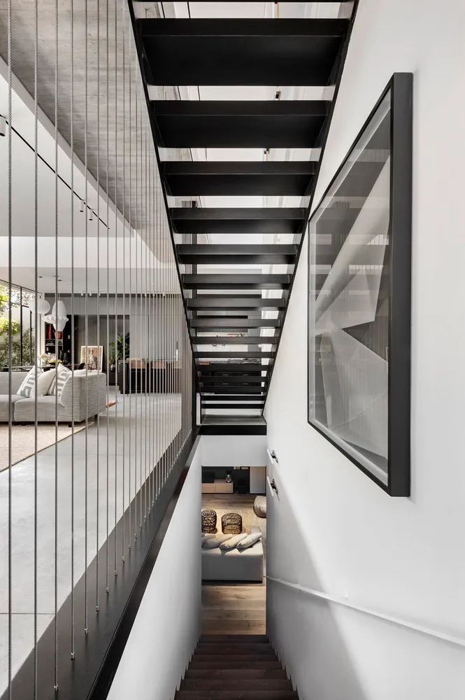 A modern residential staircase featuring black metal treads and railings.