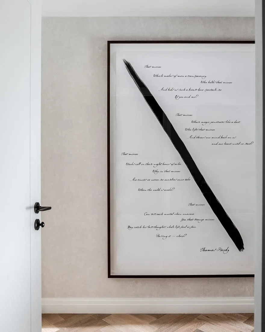 A framed piece of decorative paper with a metallic frame on a beige textured wall.