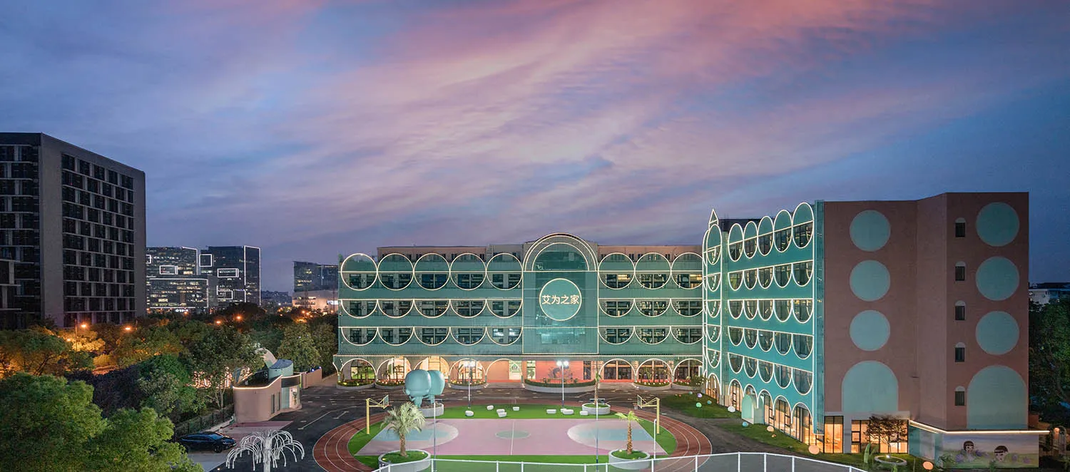 A modern office campus with a glass exterior during sunset.