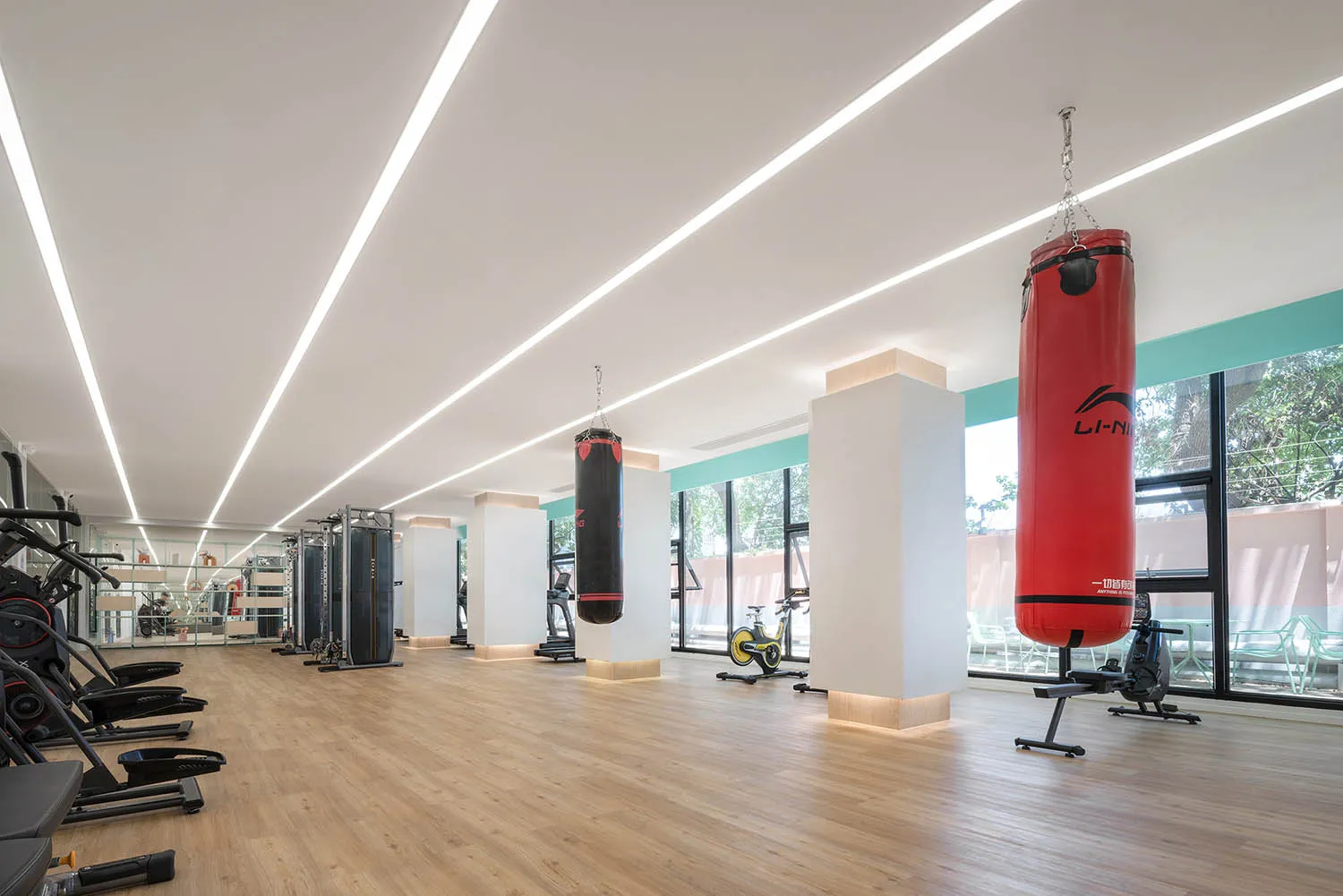 Modern minimalist gym interior with contemporary fitness equipment and boxing bags.