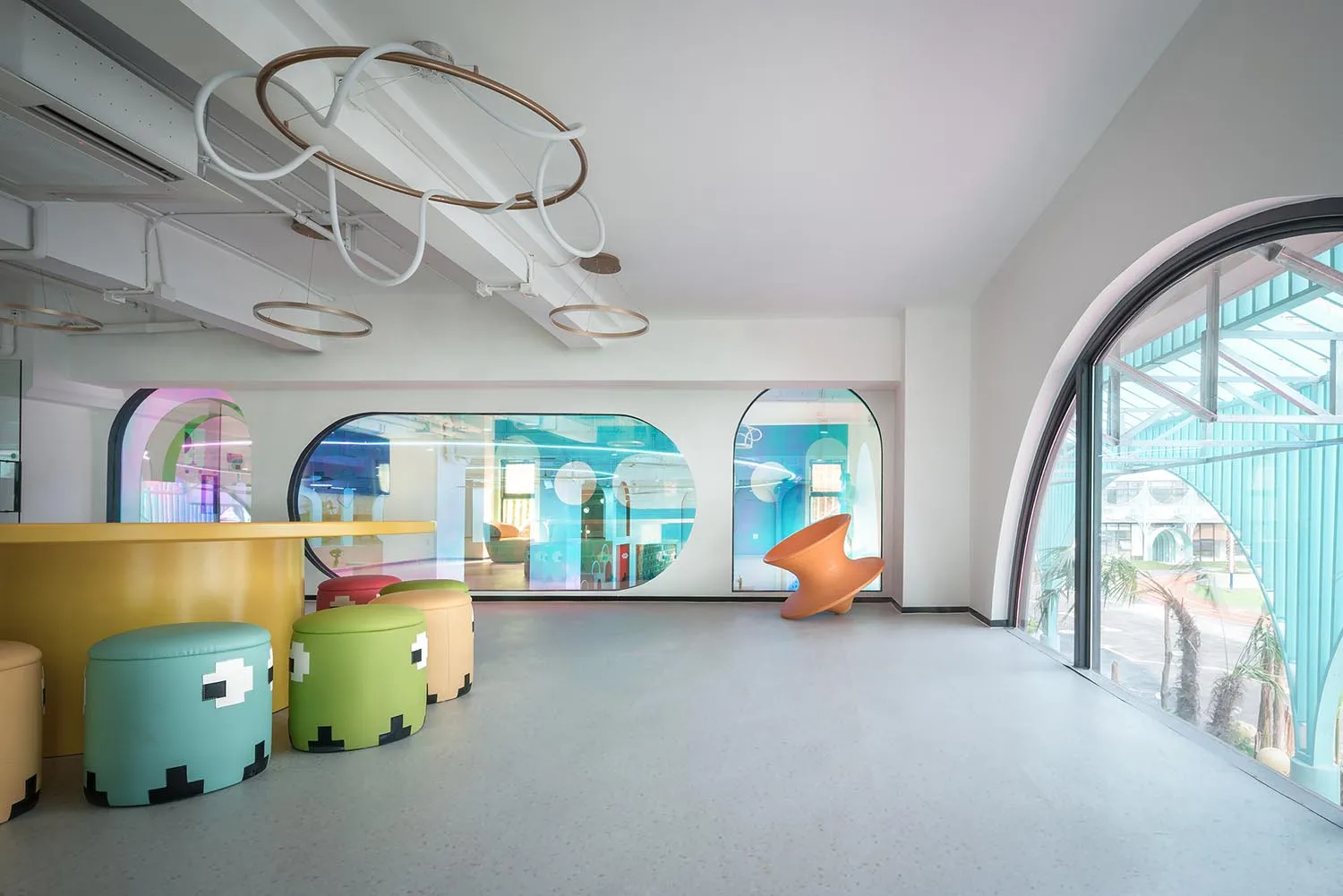 A minimalist playroom with colorful, modern furniture and large windows.