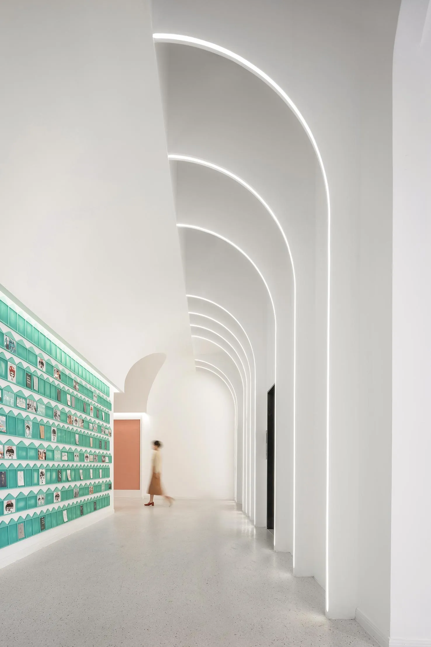 A modern interior corridor with white concrete walls and floor, featuring white concrete columns and curved arches with embed