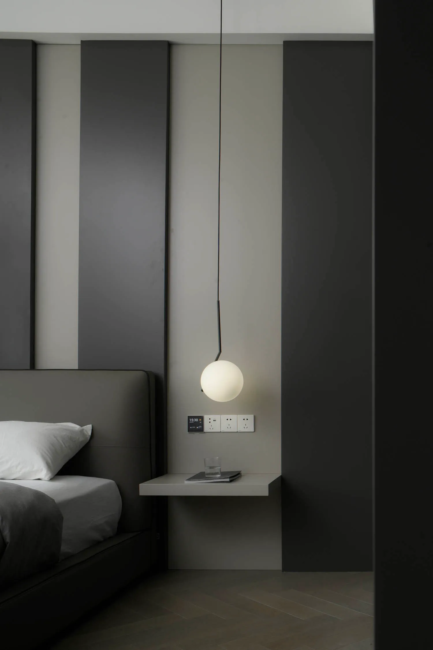 Minimalist bedroom with a metal floating light above a bed.