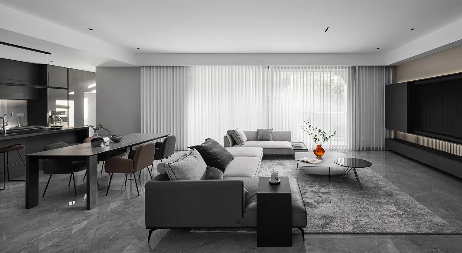 A minimalist living room featuring marble accents, fabric sofas, and a wooden dining table.