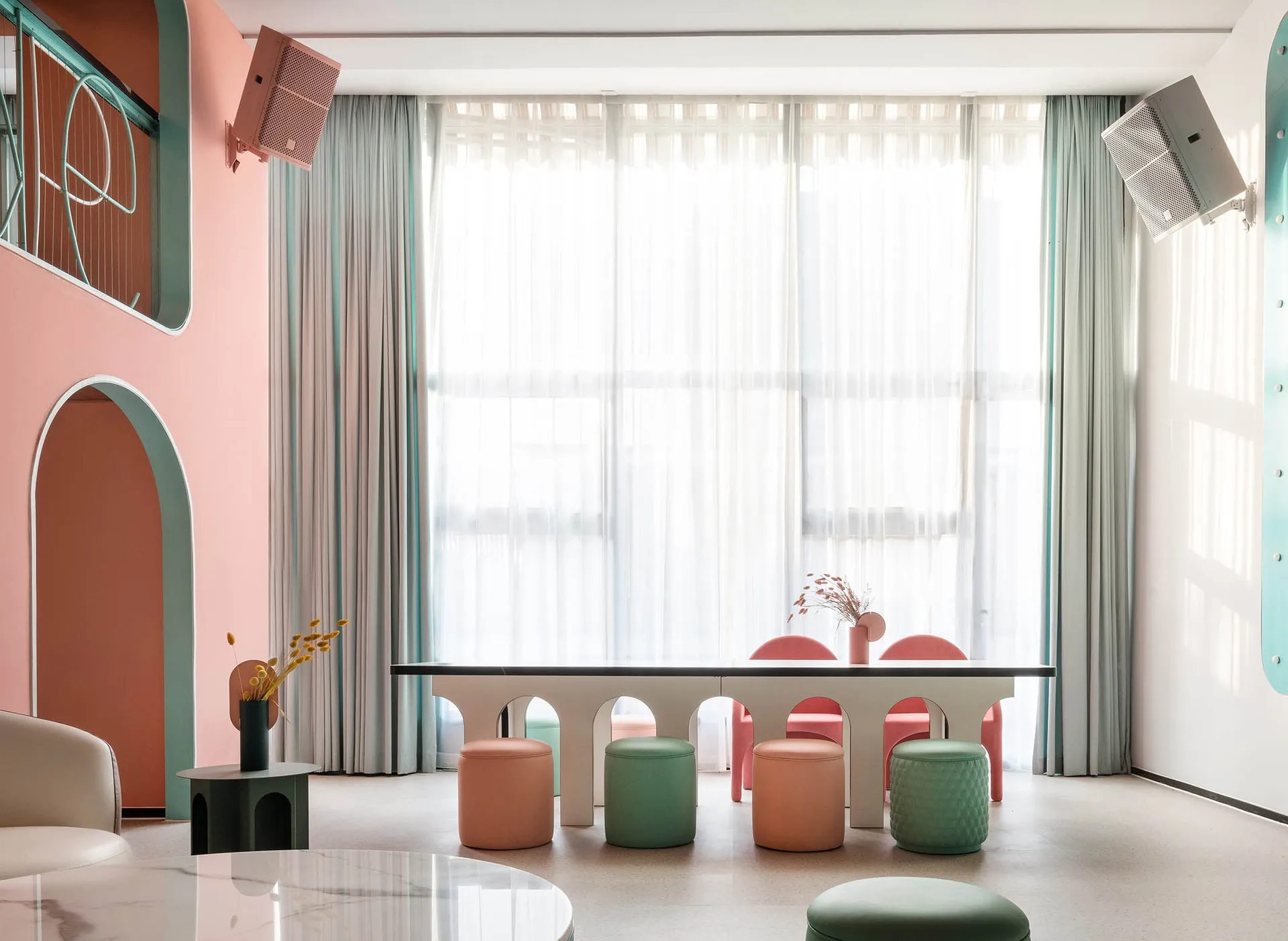 A modern minimalist restaurant with a white acrylic dining table and colorful stools.