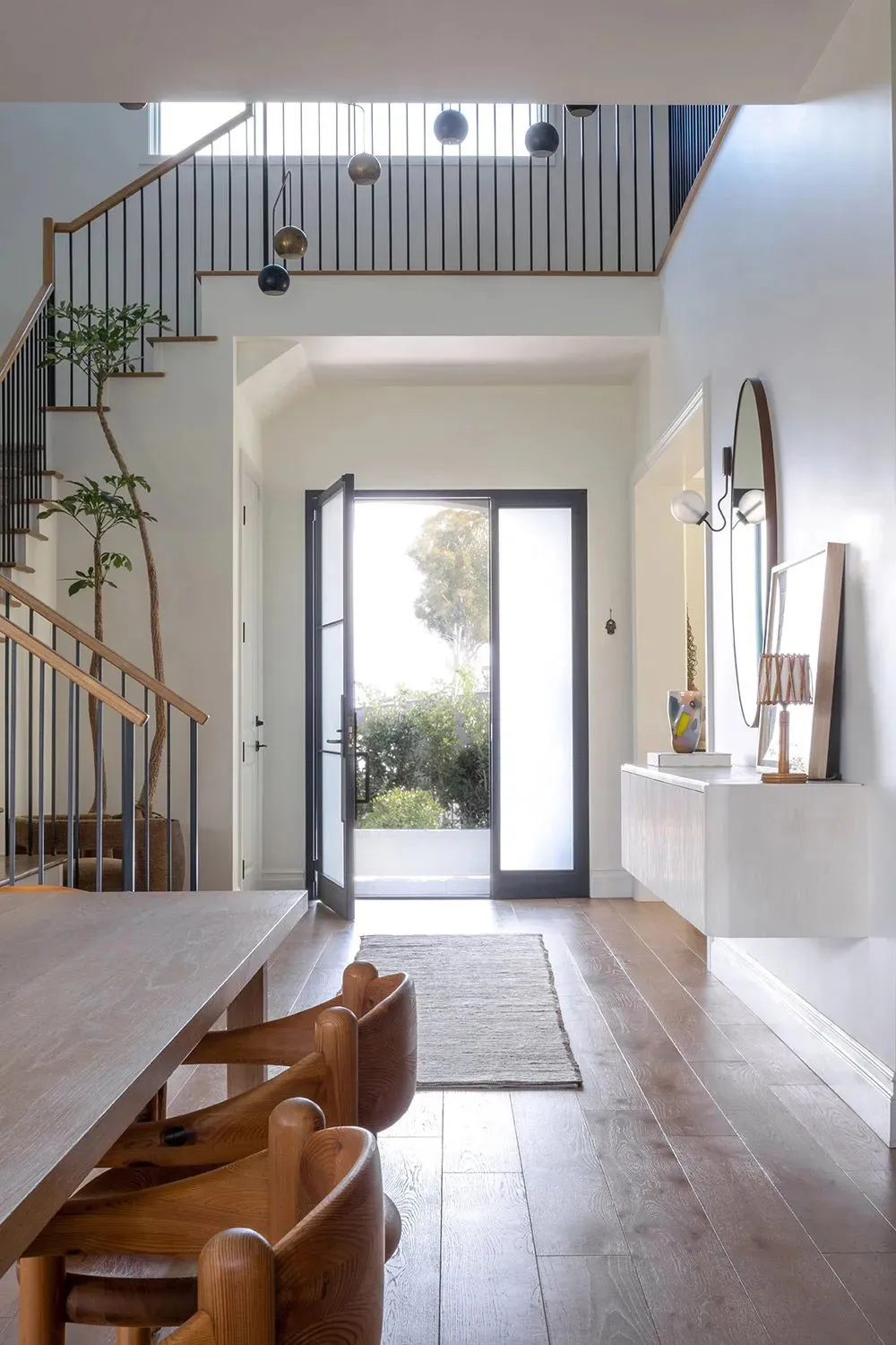 Modern dining room featuring wooden furniture and hardwood flooring, with a view of the outdoor area.