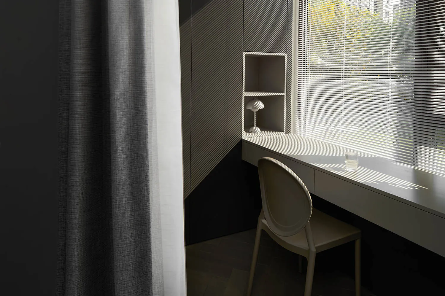 A minimalist desk space featuring a sleek, modern desk with a metal and glass tabletop, accompanied by a comfortable chair an