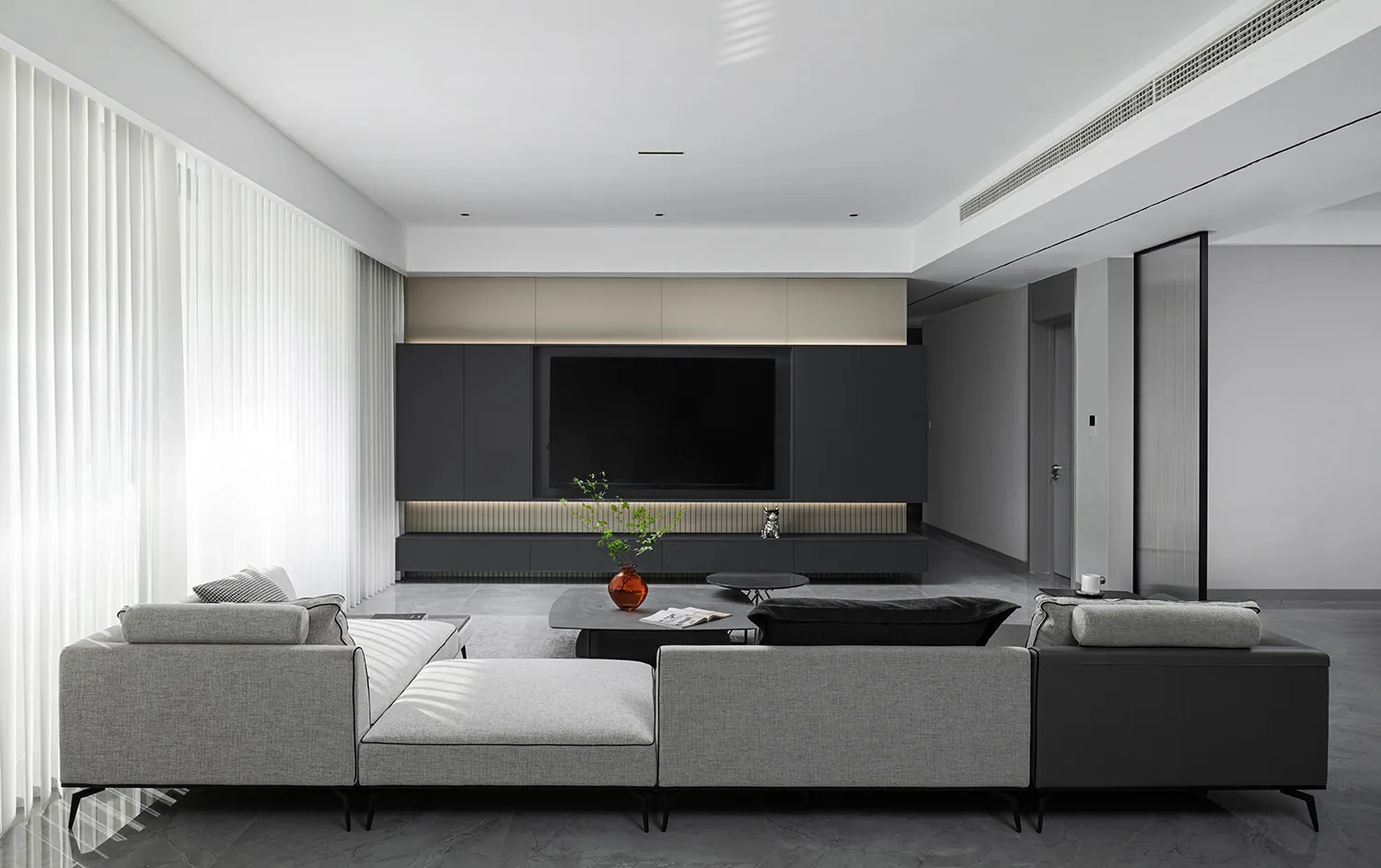 A modern minimalist living room featuring stone flooring, fabric furniture, and minimalist decor.