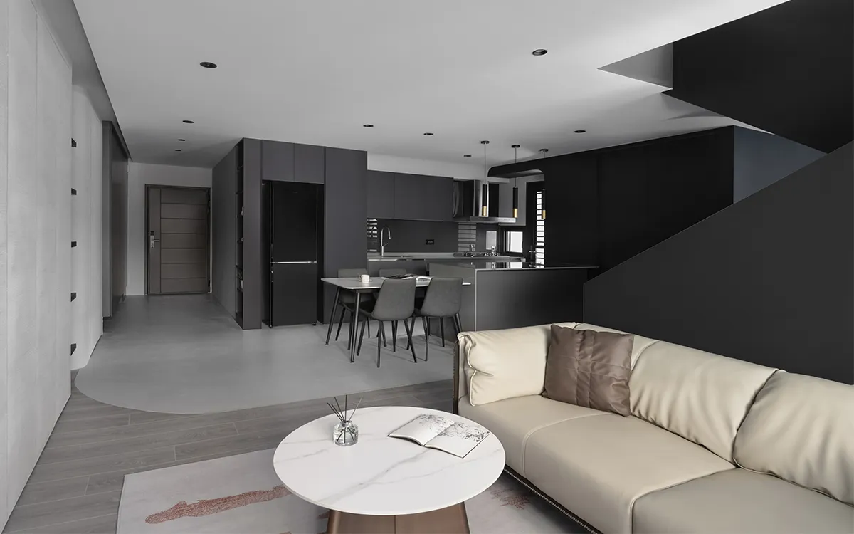 A modern minimalist living room with wood floors, concrete walls, and black furniture.