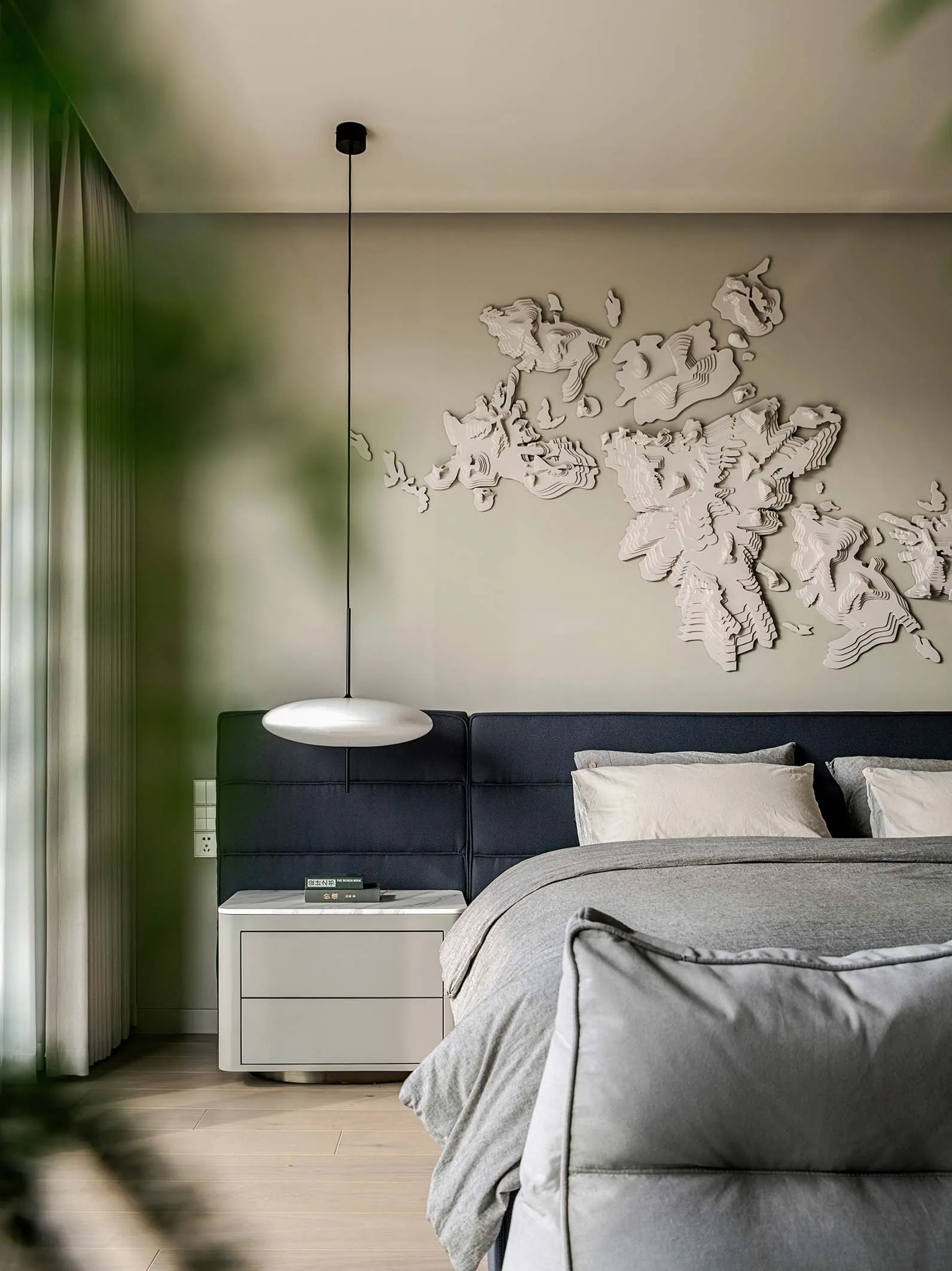 A modern minimalist bedroom featuring a fabric headboard and a wall-mounted decorative world map.