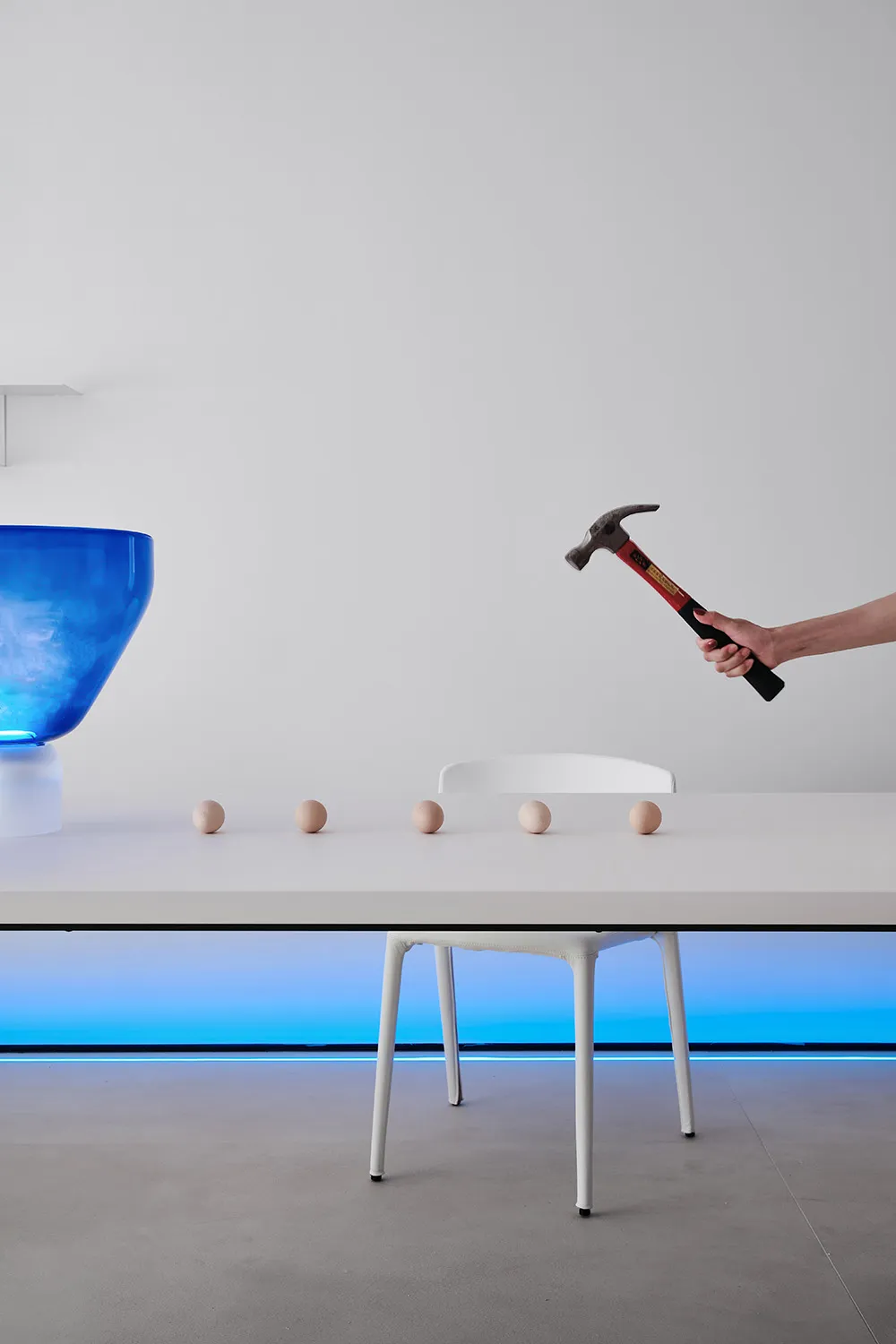 A minimalist home decor setup featuring plastic spheres and a hammer on a white table.