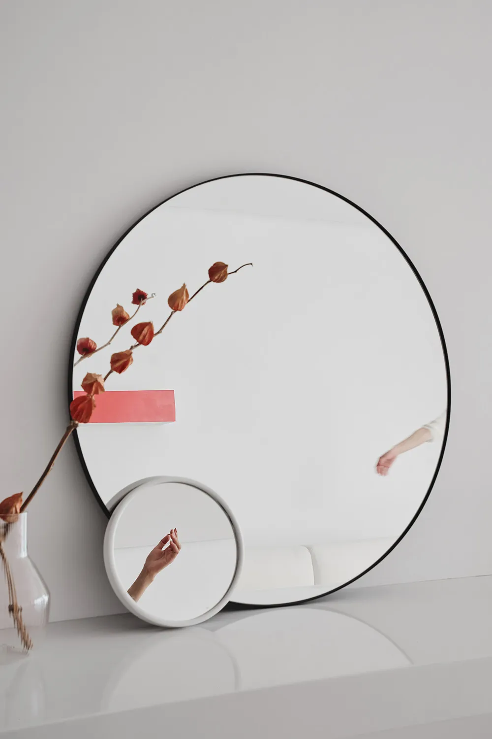 A minimalist interior design with a large circular mirror made of glass.