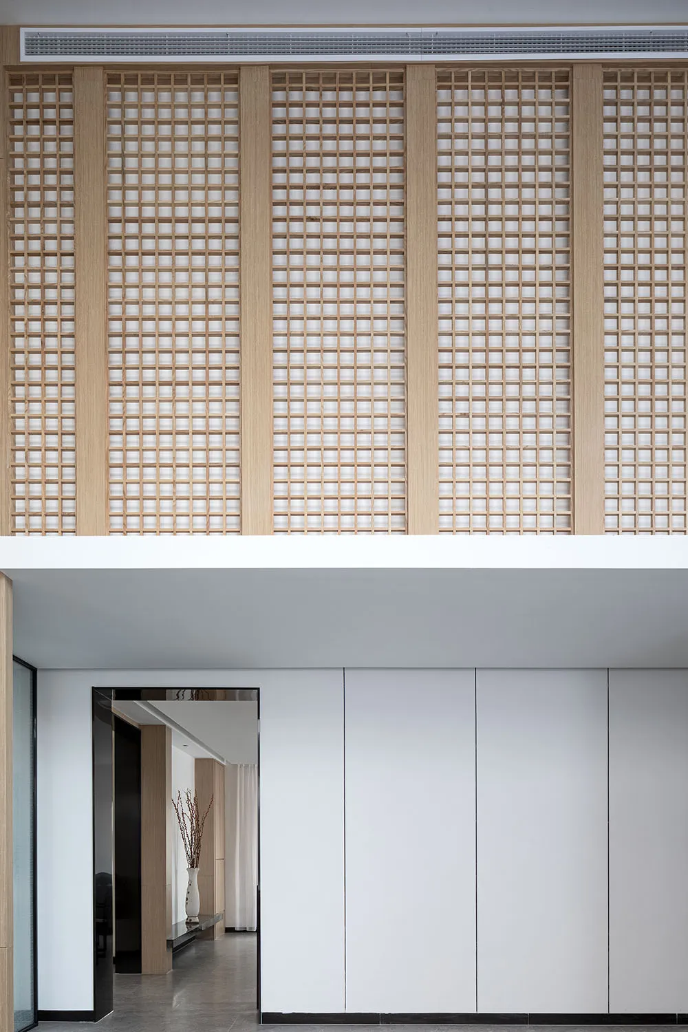 A modern entryway featuring a wooden lattice wall.