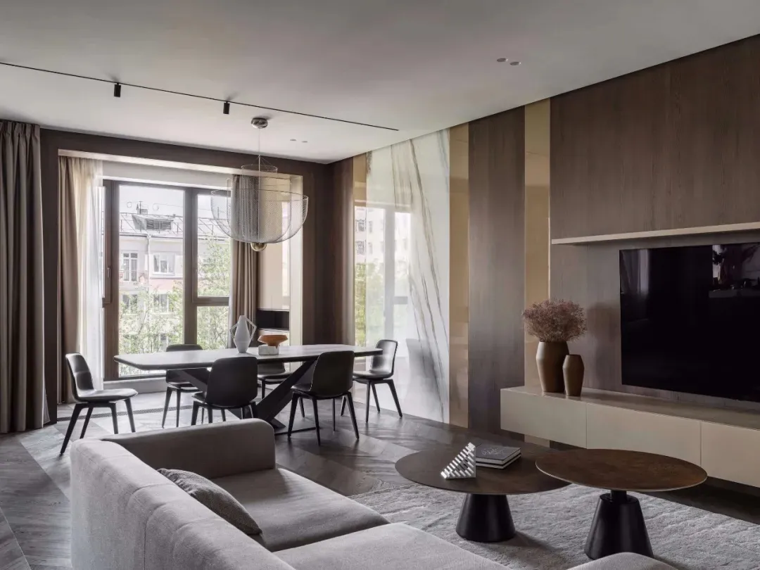 A modern minimalist living room with a white sofa, marble coffee table, and dark wood flooring.