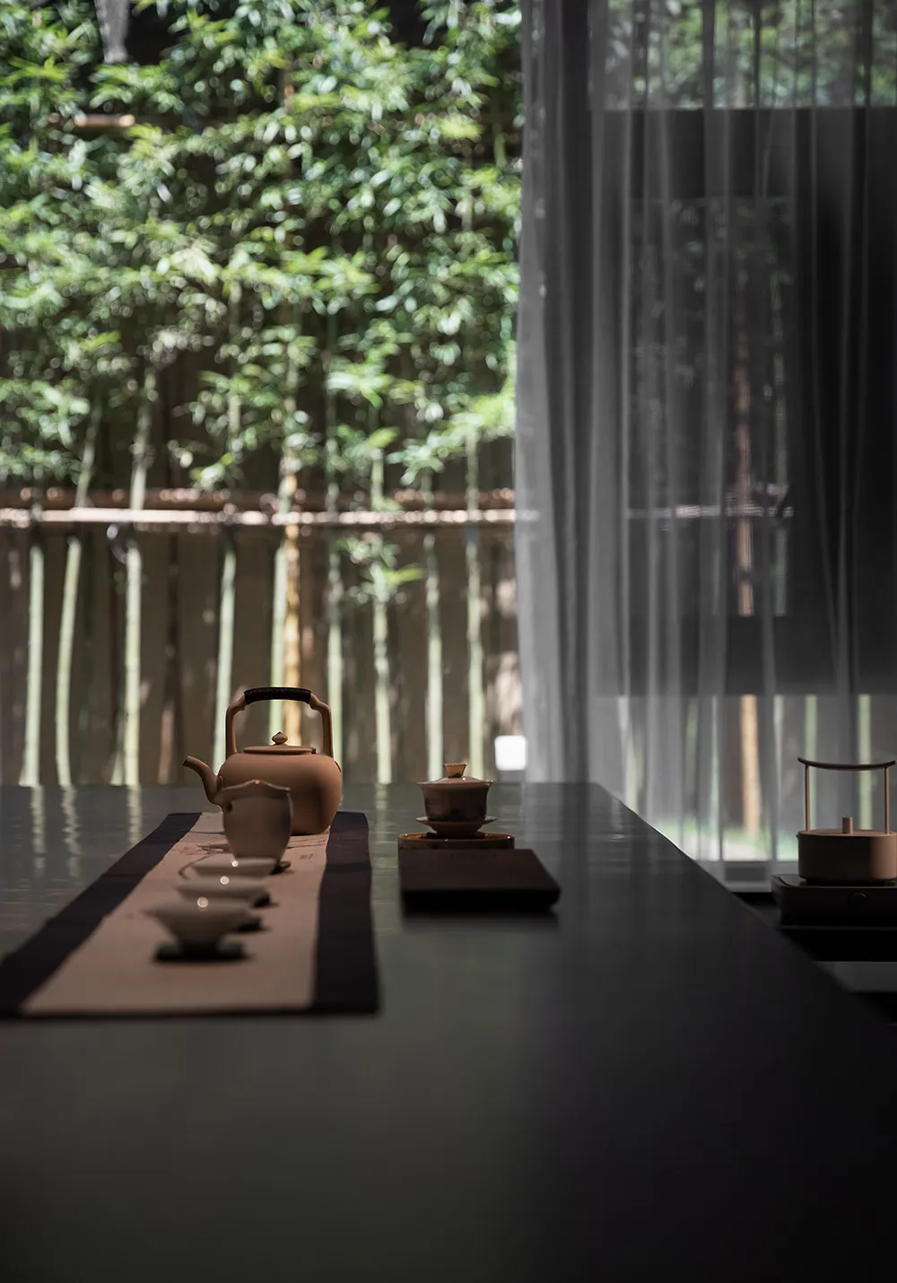 A serene tea room featuring ceramic teapot and cups, set on a table with a tea tray, surrounded by lush greenery outside.