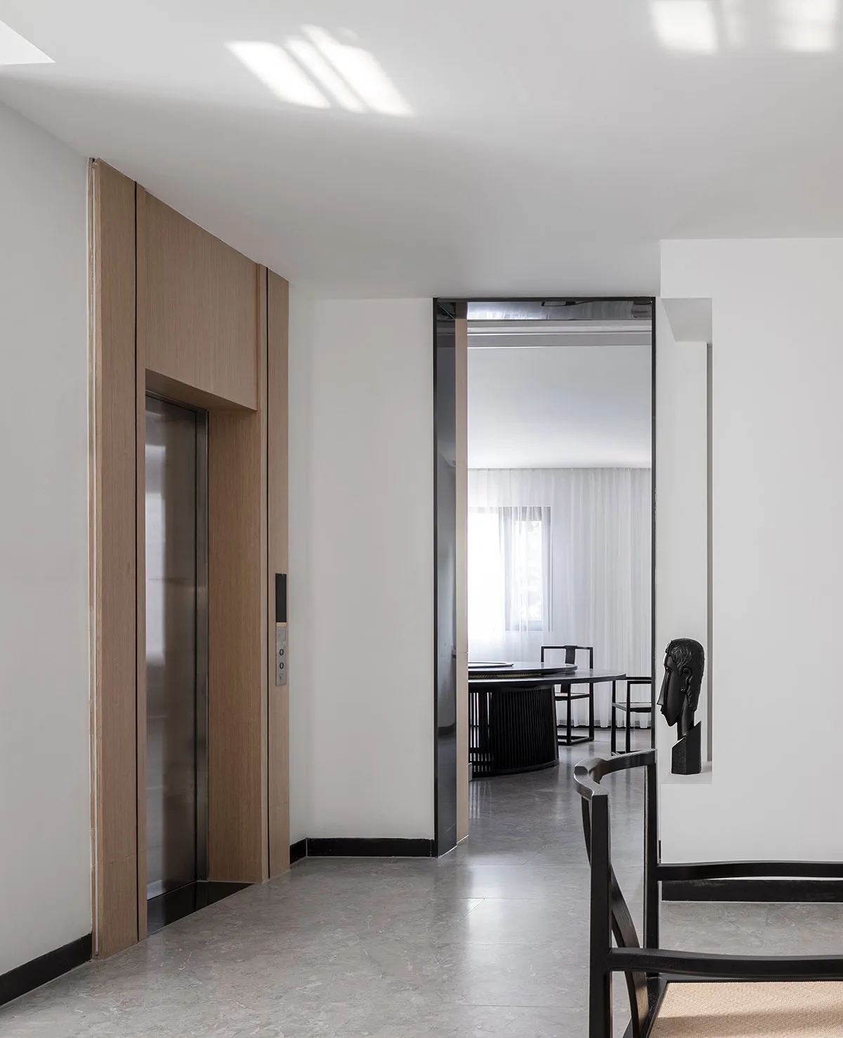 A modern entrance hall featuring wooden panels, white walls, and a door leading to another room.