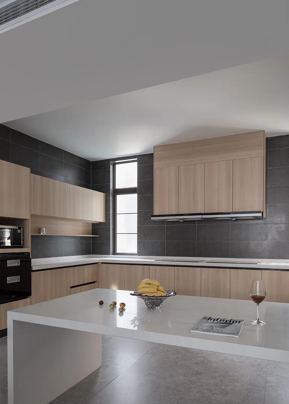 一間現代簡約的住宅廚房,搭配黑色瓷磚、木質櫥櫃與白色檯面。