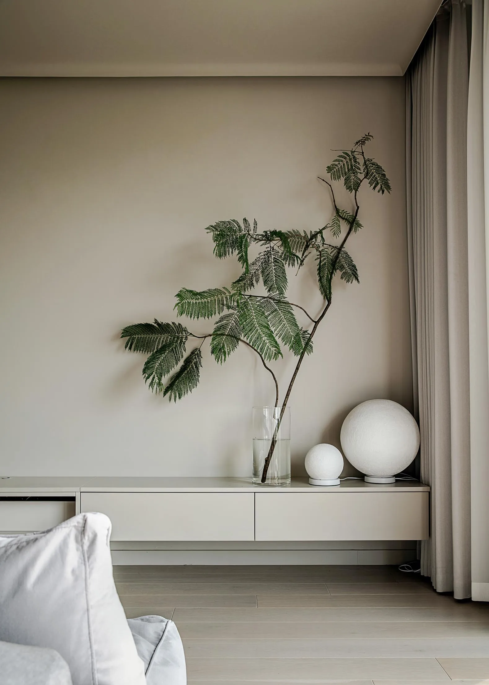 A modern living room with floating shelves, a green plant, and spherical lamps.
