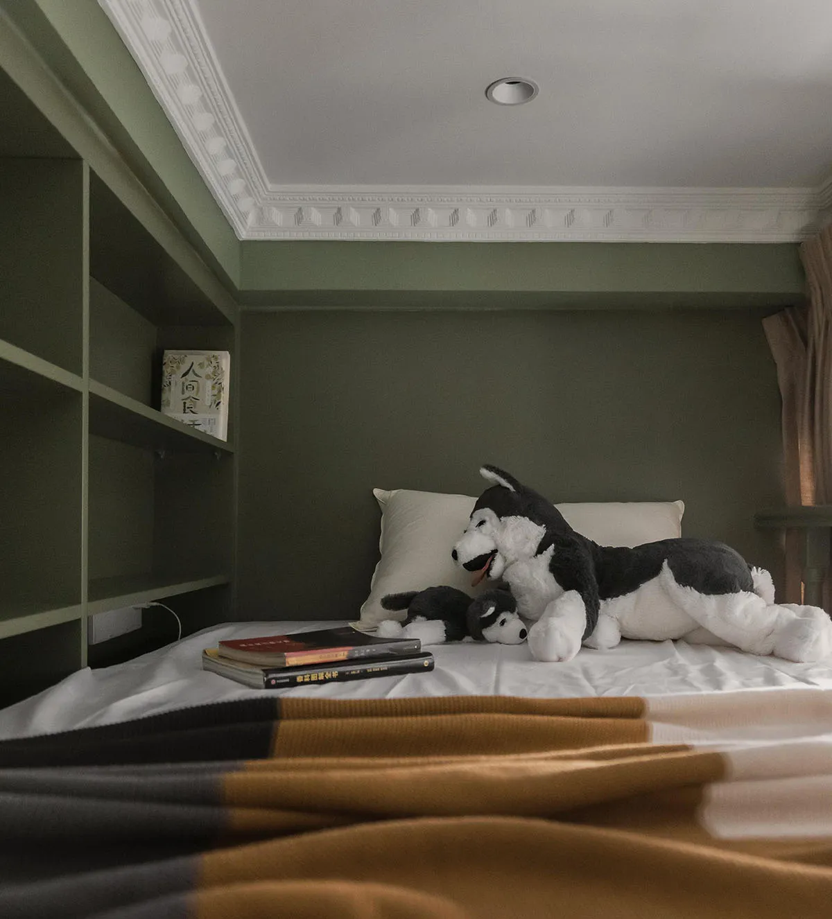Bedroom with modern design elements, including soft furnishings and books.