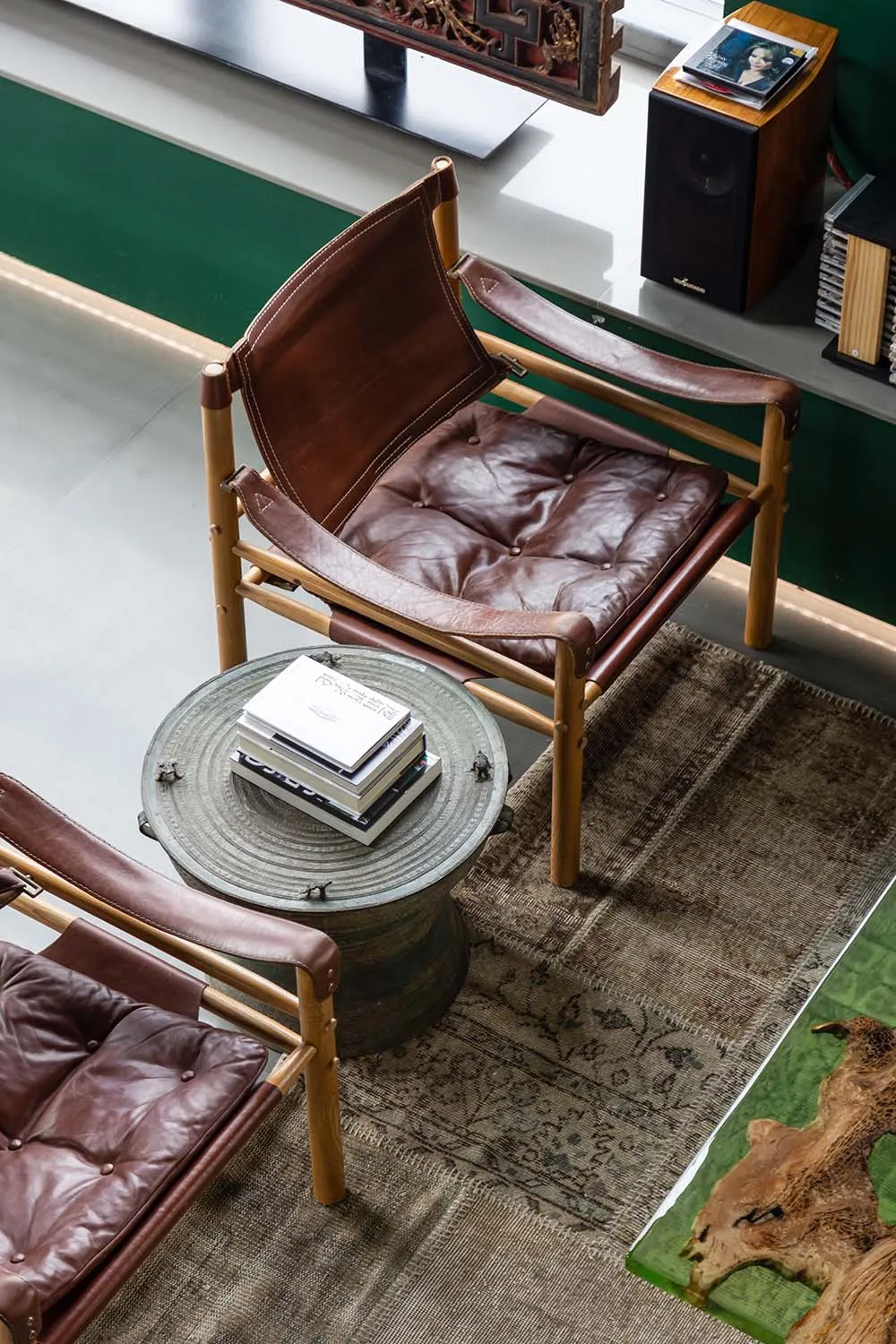 Brown leather upholstered armchair with wooden frame, placed on a woven rug in a cozy indoor living room environment.