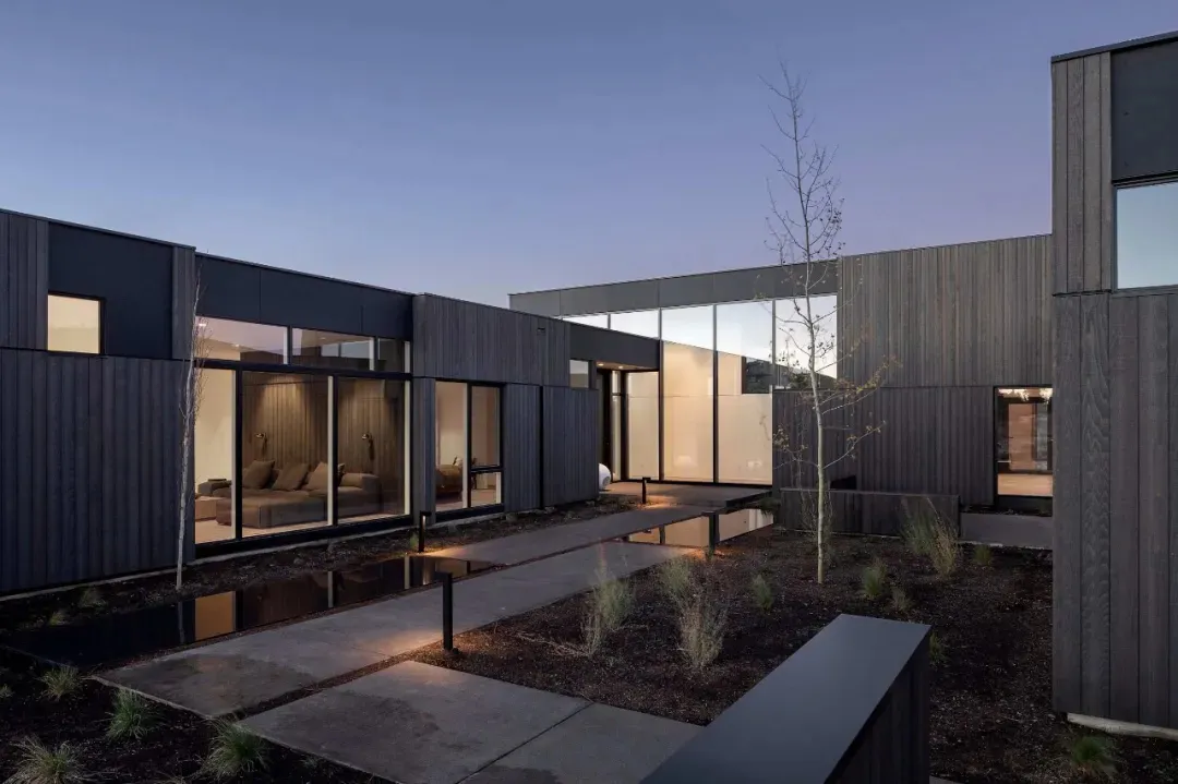 A modern house exterior featuring dark wood and glass materials.
