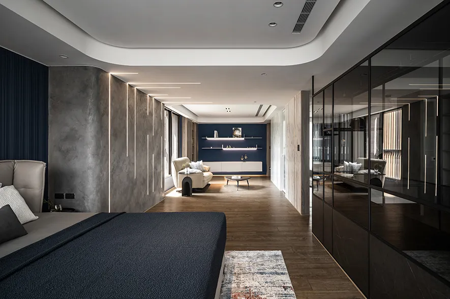 Modern bedroom with concrete walls, wooden flooring, and a blue accent wall.