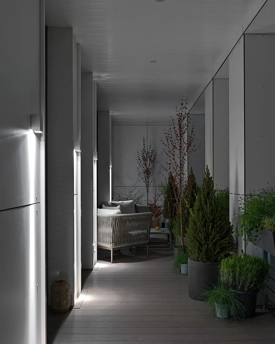 極簡風格的室內庭院，搭配木質平台、白家具與盆栽植物。