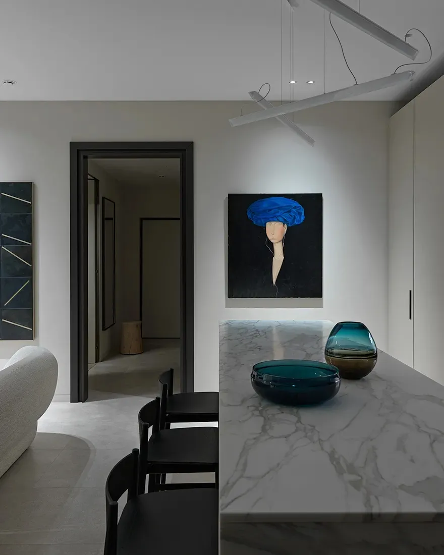 A modern, minimalist kitchen interior featuring a marble counter top with two glass bowls.