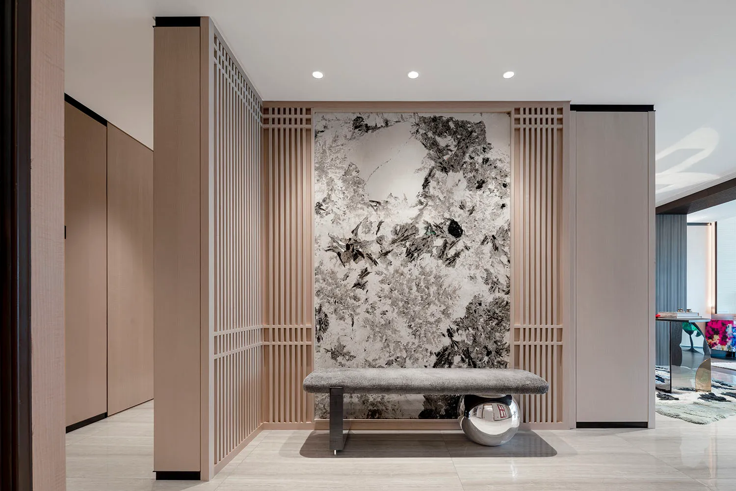 Modern entrance hall featuring a marble wall and bench.