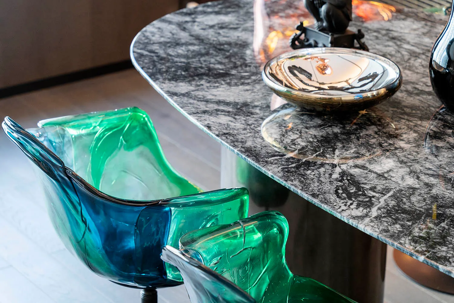 Modern interior design featuring glass chairs and a marble table.