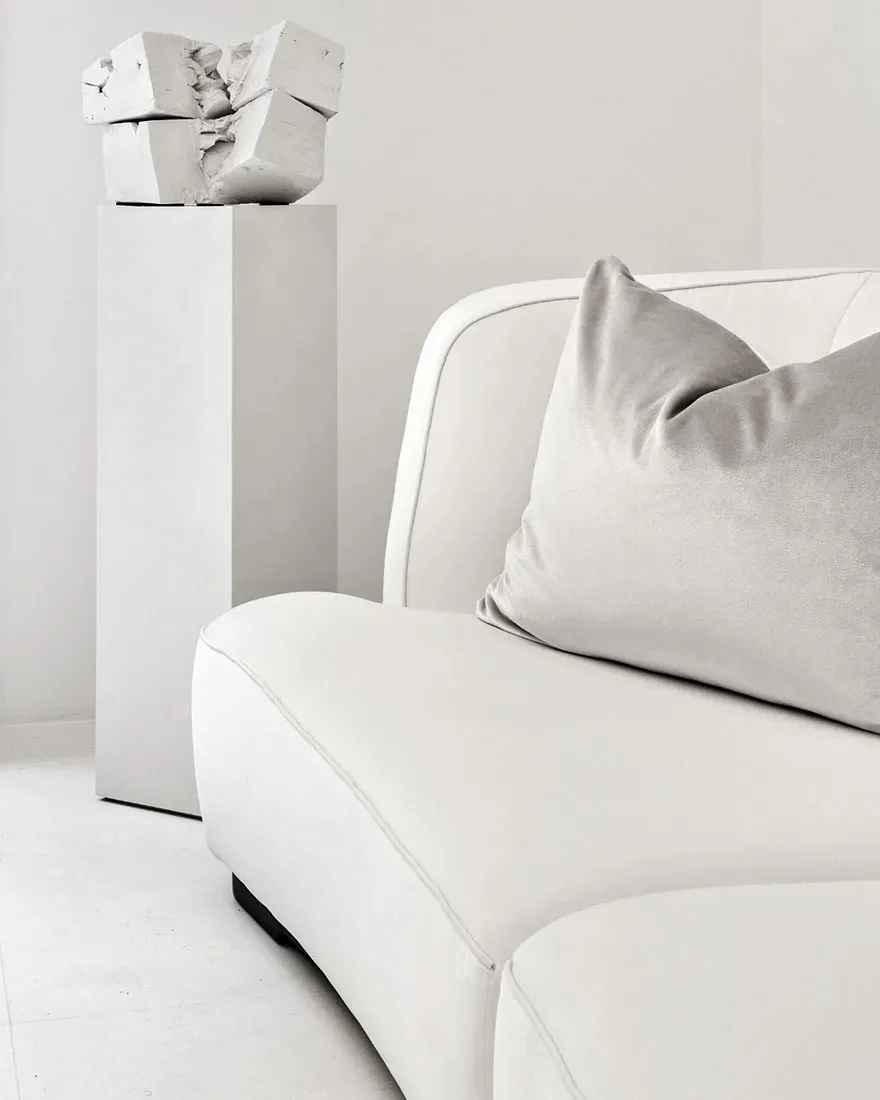Contemporary living room with a modern white couch, grey throw pillows, and a geometric concrete sculpture
