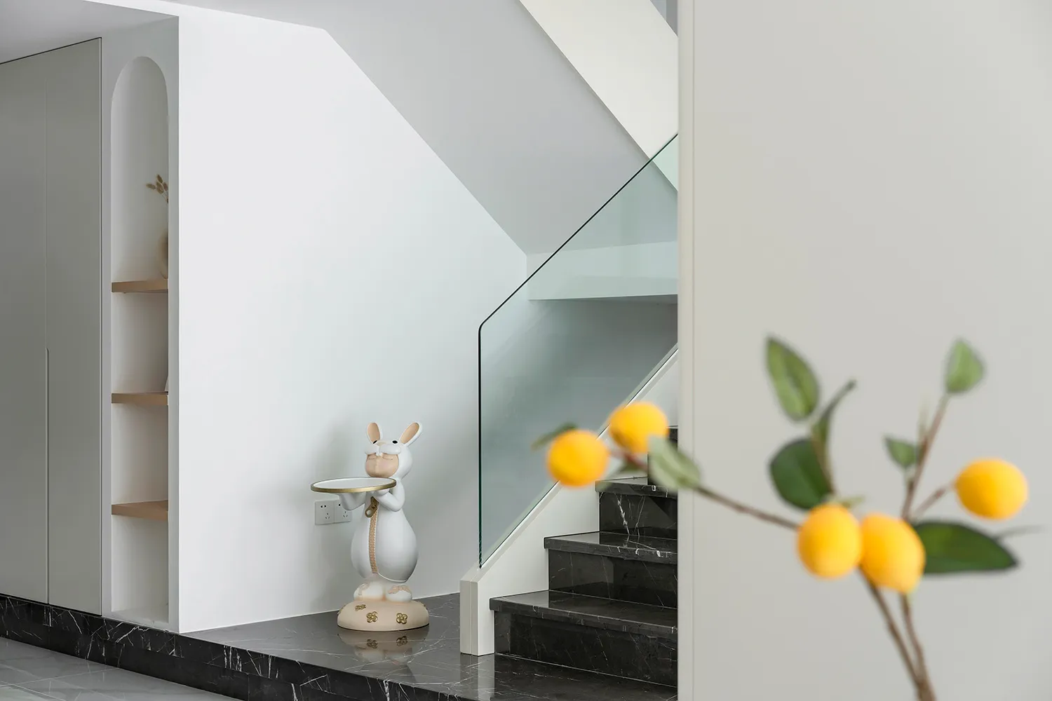 Modern minimalist staircase featuring marble steps and railings with glass railings.