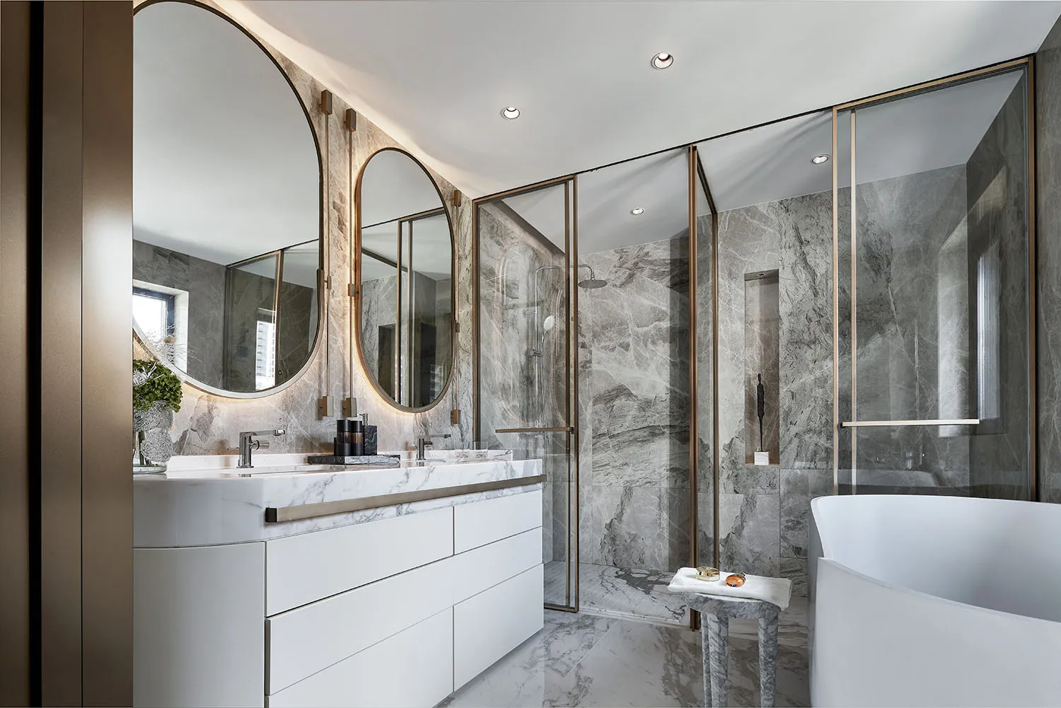 A modern bathroom featuring marble walls and flooring, a glass shower enclosure, and a white bathtub.