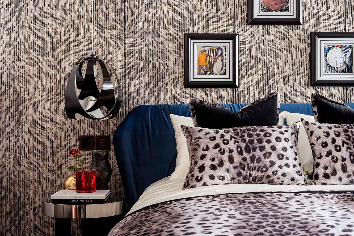 Modern bedroom with leopard print bedding, blue headboard, and abstract artwork hanging on the wall.