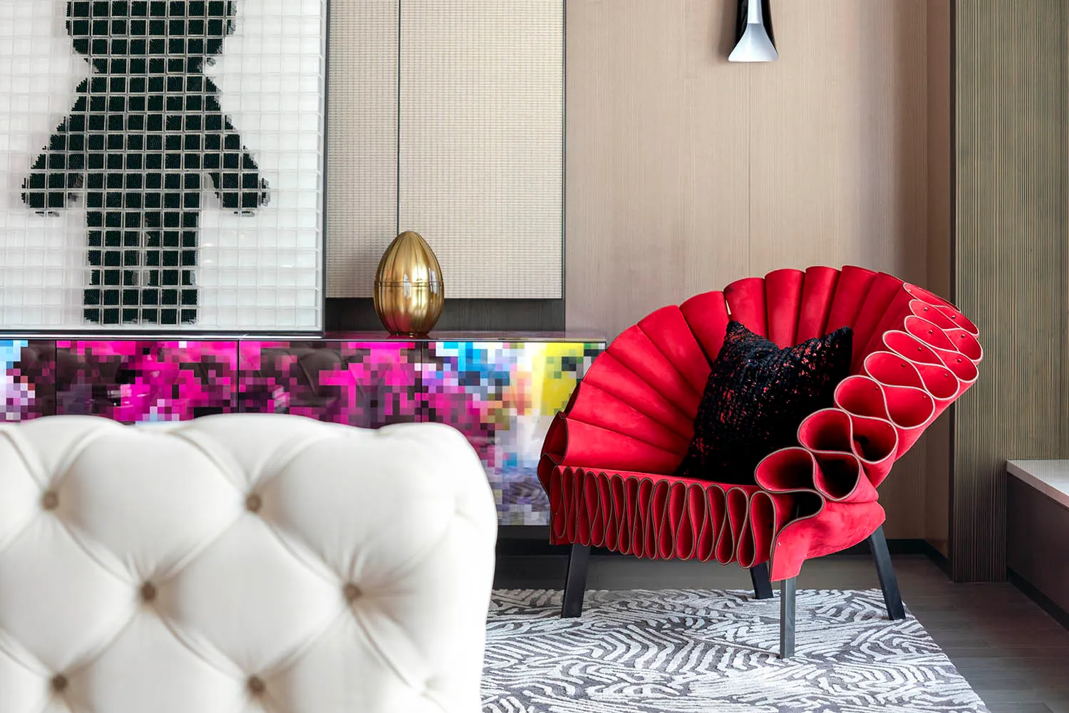 A red, contemporary armchair with black and white patterns on a rug in a living room.