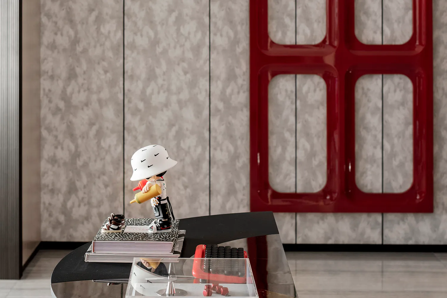 A decorative figurine holding a yellow tube on a book stack placed on a terrazzo floor.