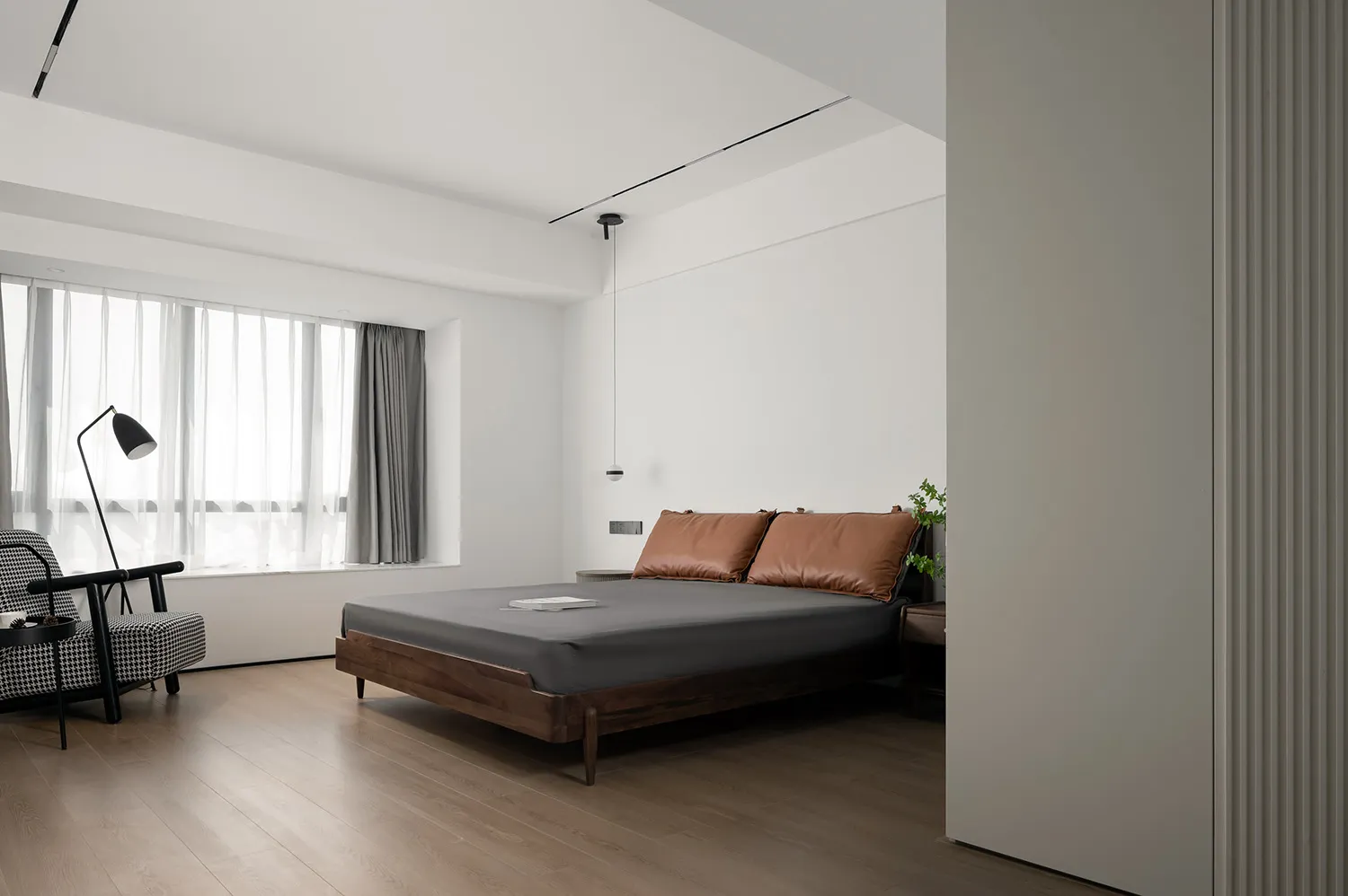 A minimalist bedroom featuring a wooden bed frame, leather headboard, and glass window with sheer curtains.