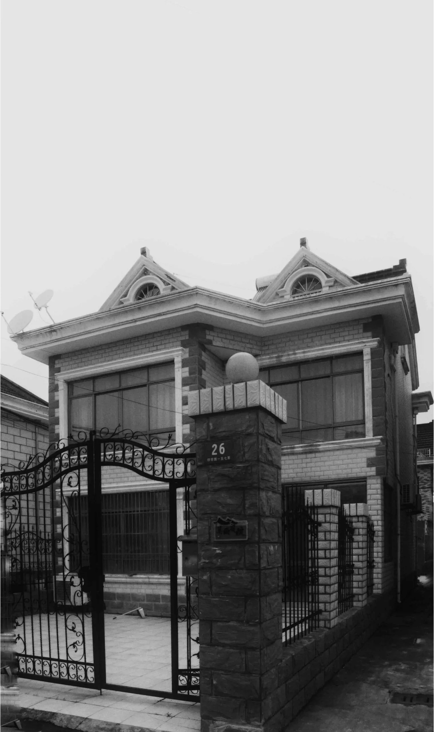一棟現代住宅,外牆採用磚塊與混凝土材質,具雙層樓設計並設有大門入口。