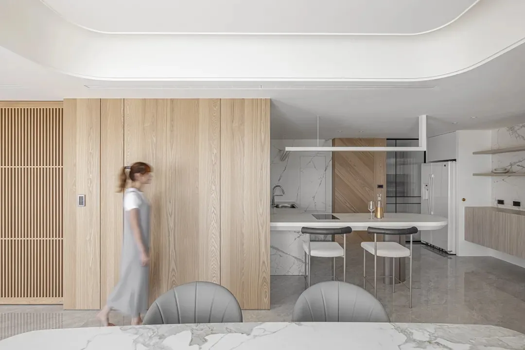 A modern kitchen with marble countertops, wood cabinetry, and stainless steel appliances.