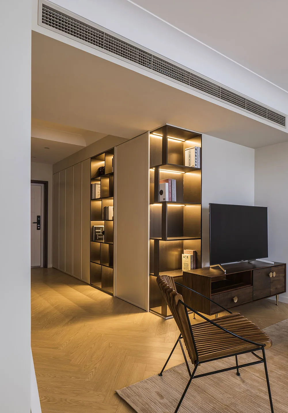 A modern living room featuring wooden shelves with books and decorative items.