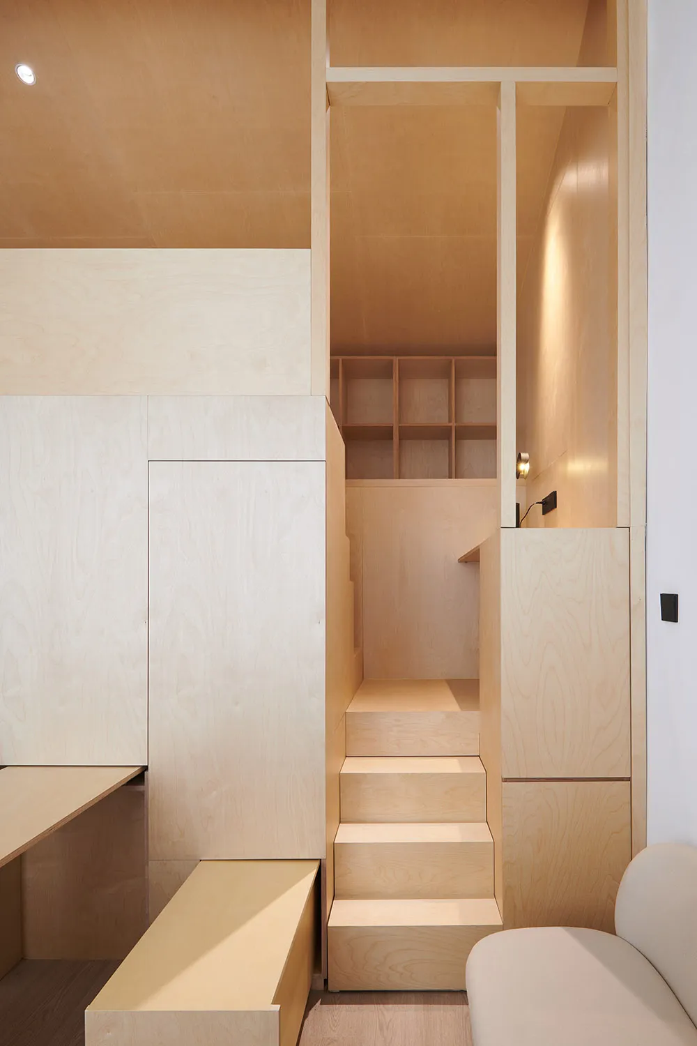 A minimalist residential interior with wooden stairs and storage units.