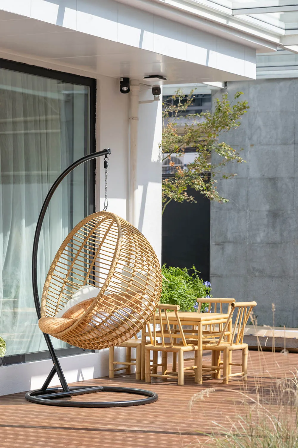Bamboo-woven hanging chair and wooden dining set on a wooden patio