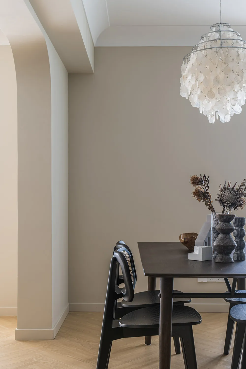 Modern dining room featuring a marble table with black chairs and a large, decorative chandelier.